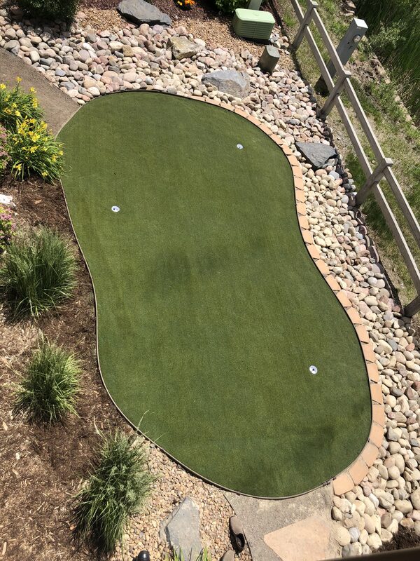 Overhead view of the finished artificial putting green showing two cups and the kidney shape