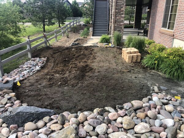 Turf stripped back to soil and re-graded, river rock border retained